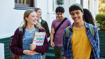 A group of diverse teenagers walking outside and smiling together, demonstrating healthy screen time balance and positive youth wellness habits.