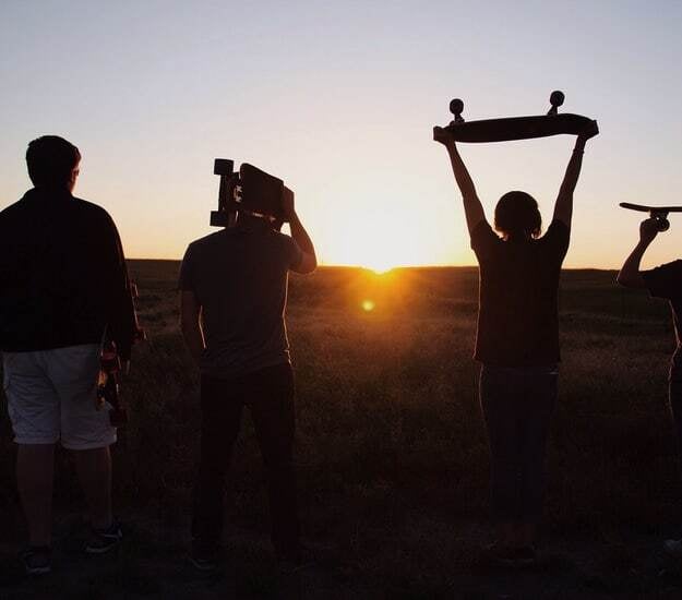 kids with skateboards in front of a sunset