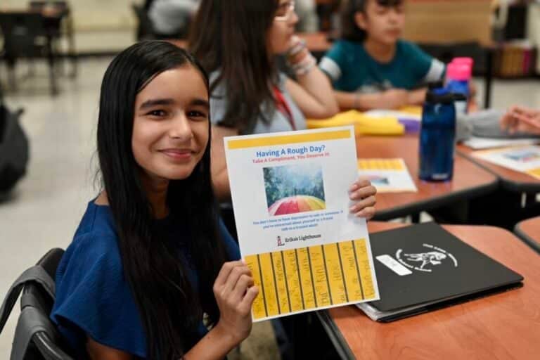 young girl proudly holding up her work