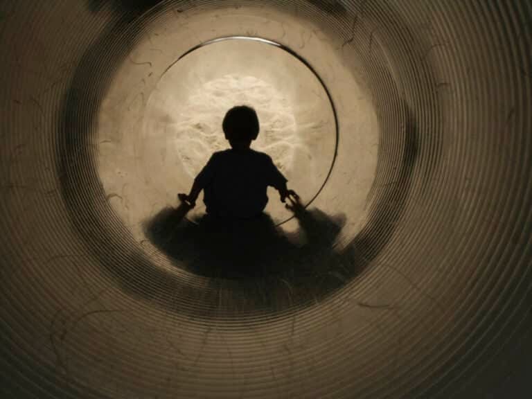 young child sitting at the end of a tunnel