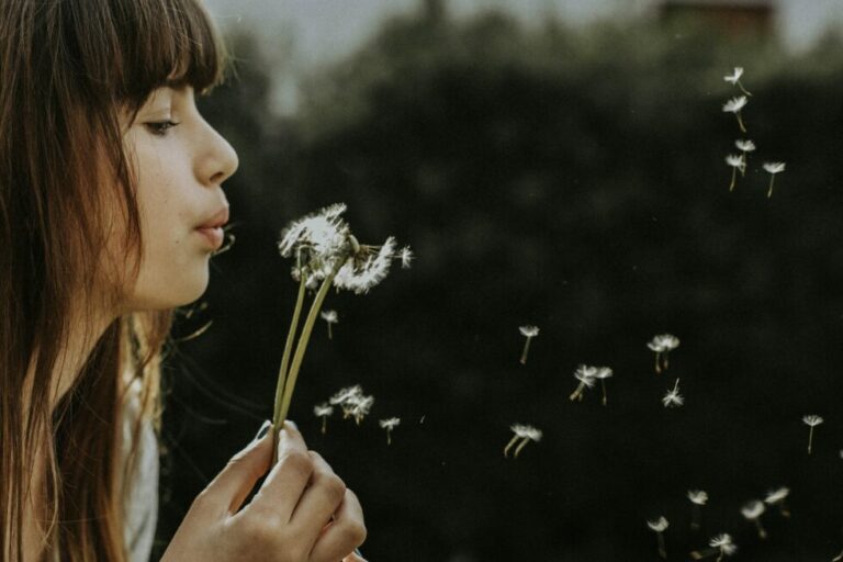 girl blowing dandelion