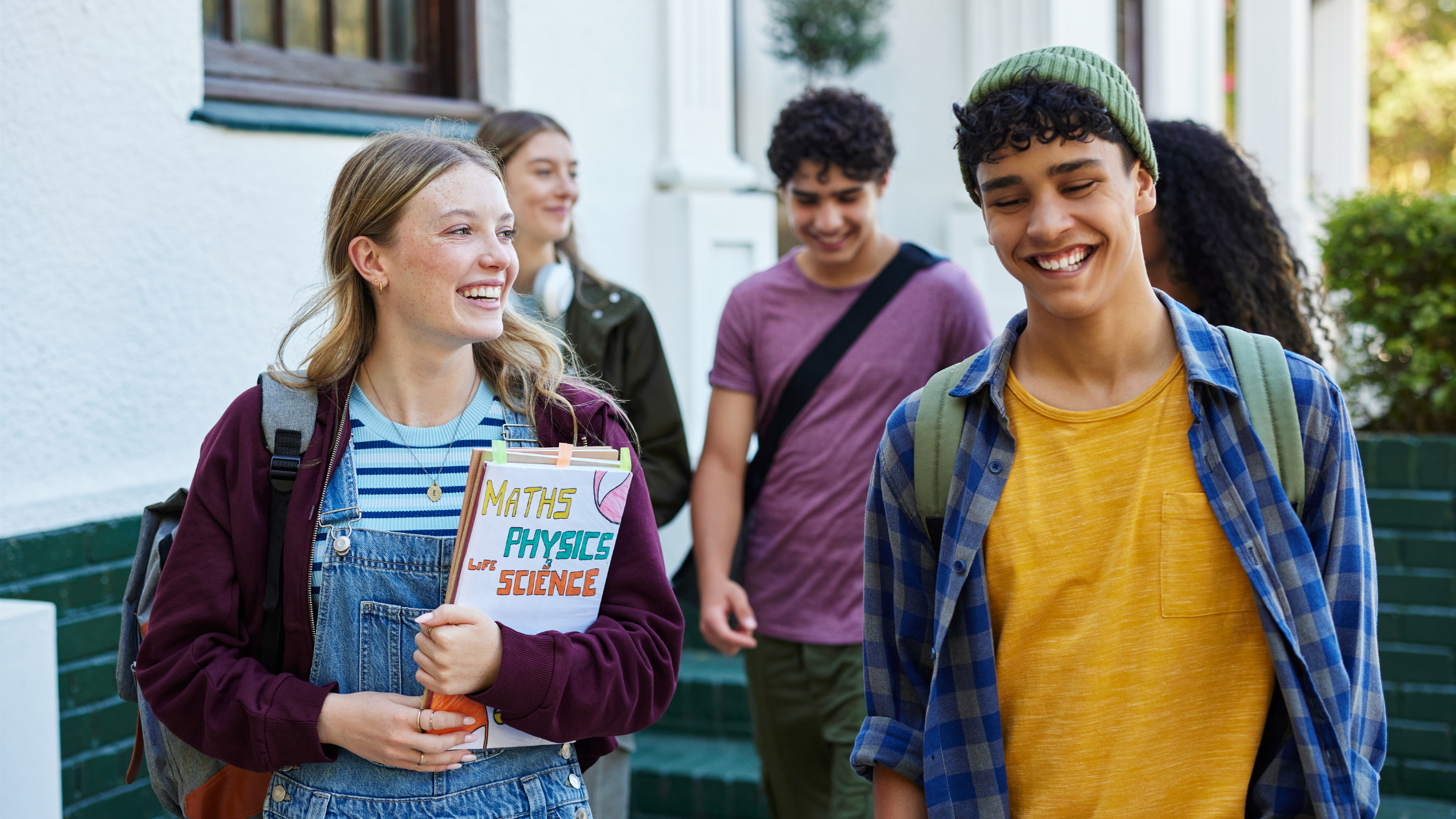 A group of diverse teenagers walking outside and smiling together, demonstrating healthy screen time balance and positive youth wellness habits.