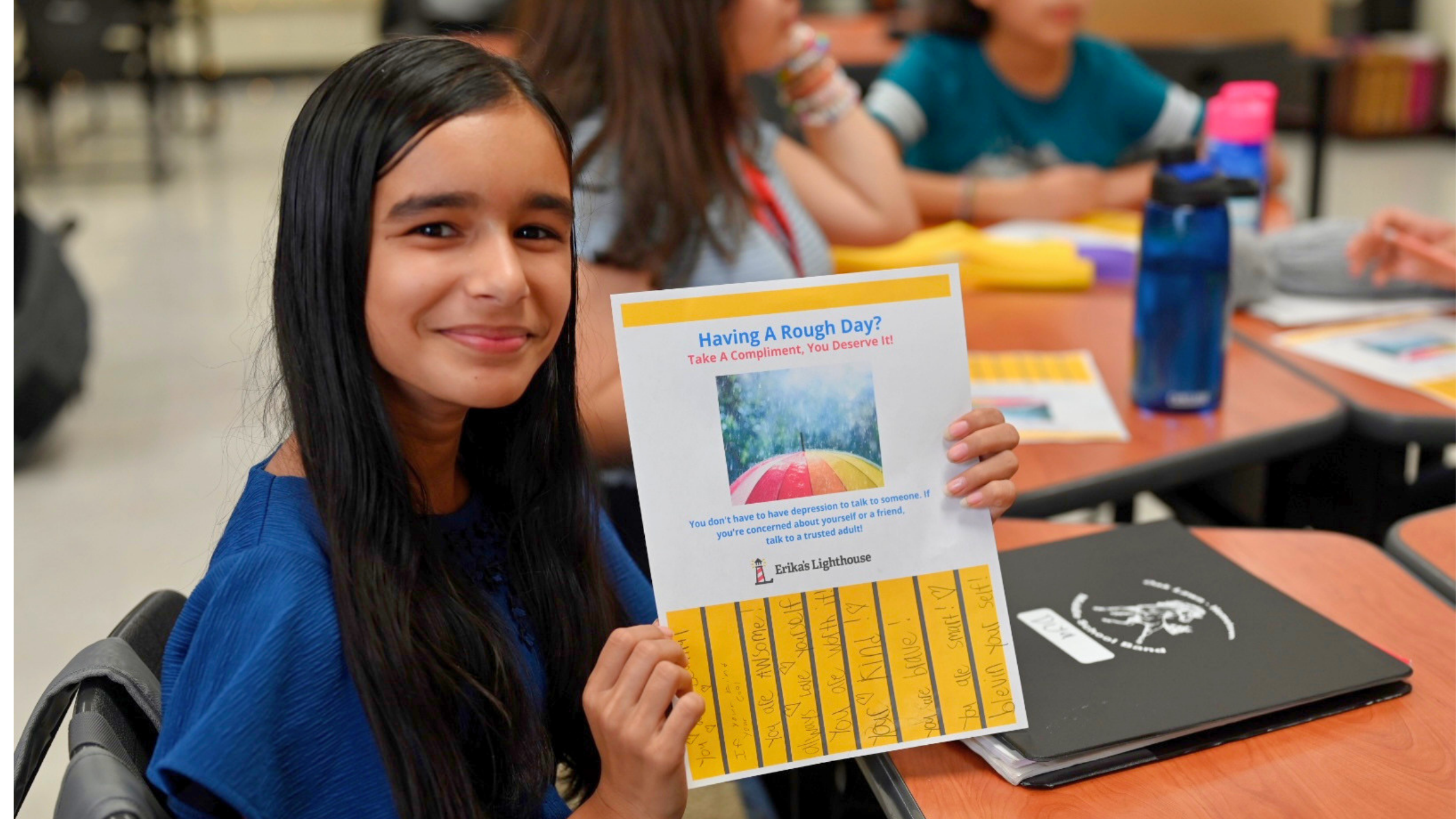 Student participating in an Erika's Lighthouse mental health education program while holding a classroom activity focused on help-seeking and trusted adult support.